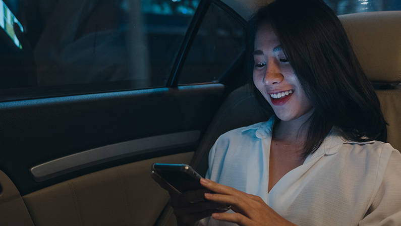 Successful young Asia businesswoman in fashion office clothes using smart phone in sitting back seat of car in urban modern city in night.