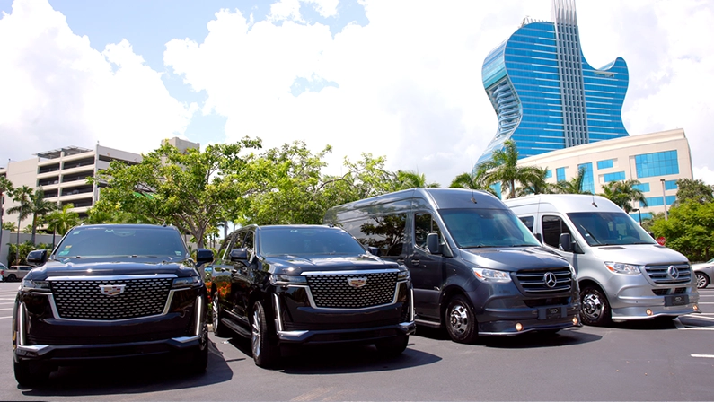 Fleet of luxury SUVs and vans for chauffeur services in Miami, parked in front of a Hotel.