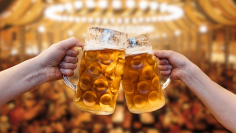 Men clinking mugs with beer during celebration of Oktoberfest outdoors, background.Cheers with beer and enjoy tradition.