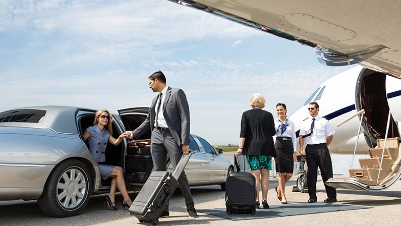 Business partners about to board private jet while airhostess and pilot greeting them