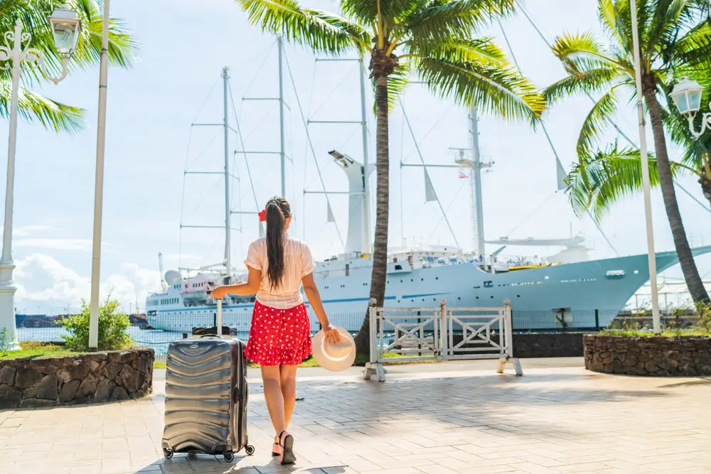 Cruise travel passenger going on board embarking ship with luggage suitcase. 